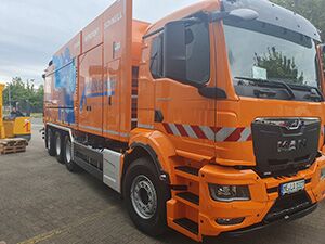 Saugwagen - Apken GmbH Ein großer orangefarbener Saugwagen steht vor einem Gebäude geparkt.