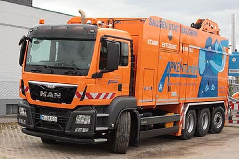 Ein großer orangefarbener Saugwagen von vorne rechts.